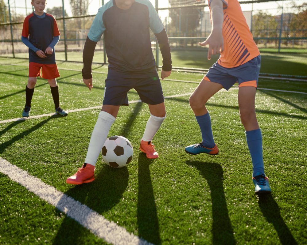 Young boys playing football soccer match at training camp for kids. Sports tournament for youth team