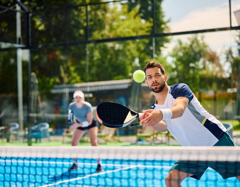 Young athletic man playing padel on outdoor tennis court.